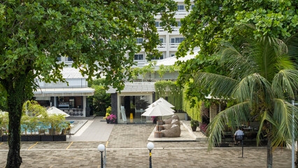 Tropical resort lounge with palm trees, outdoor bean bags, pool bar, and green vertical garden....