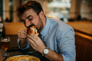Businessman eating burger and french fries in restaurant