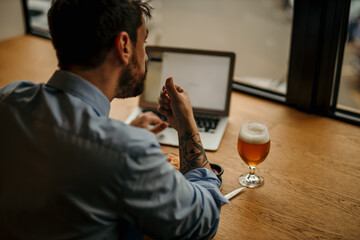 Businessman working on laptop with beer and food in cafe