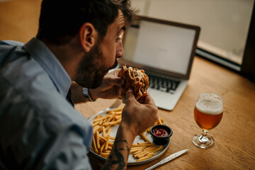 Office worker eating burger and french fries at lunch break in restaurant