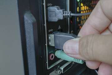 Person is connecting USB cable into computer port, showcasing technology and connectivity. image...