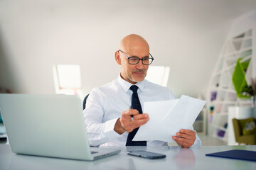 Caucasian man with laptop sitting at office desk and working