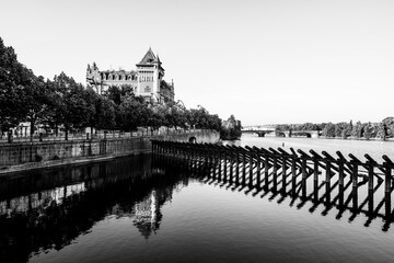 Visitors stroll along Smetana Embankment in Prague, admiring the tranquil waters of the Vltava...