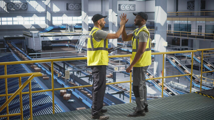 Diverse African and Multiethnic Arab Men High Five In Front of  An Automated Conveyor Belt Load. Warehouse Associates at Work
