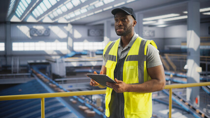 Black Employee Working at a Modern Logistics Center for an International Online Shopping Platform. African Man Using a Laptop Computer to Optimize the Orders Before Deliveries