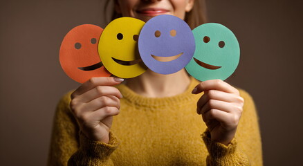 Woman holding colorful smiley face cutouts. Customer feedback survey concept showing joy and satisfaction. Group of happy emoji for review.