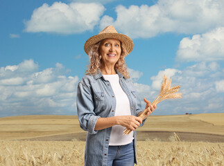 Happy woman holding a bunch of wheat stalks