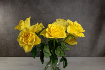 Vibrant Yellow Roses in a Glass Vase on a Wooden Table