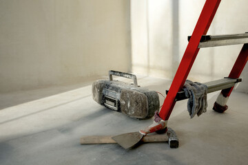 Fototapeta premium renovation. grey background. Repair concept. Red ladder stepladder. renovation. grey concrete background.