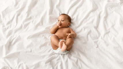 Teething Concept. Top above high angle view portrait of little African American infant wearing...