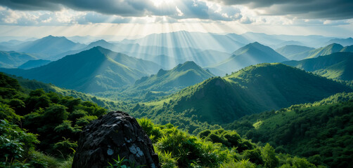 A breathtaking panorama of lush green mountains bathed in sunlight.  Crests and valleys stretch into the distance, creating a serene and majestic landscape.