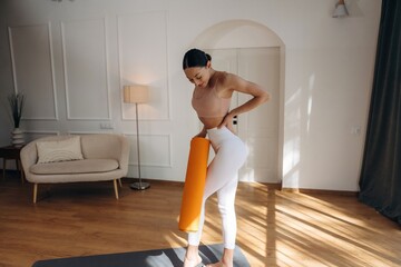 The orange fitness roll. Young woman in fitness clothes is in the room