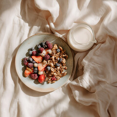 Vegan breakfast with granola, berries and non-dairy milk on soft fabric background in natural morning light, ideal for food blogs, lifestyle branding, healthy living promotions.  cozy, minimal