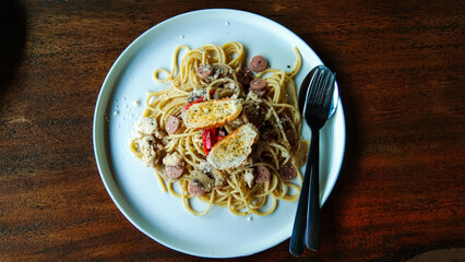 Spaghetti on a white ceramic plate with a wooden table background