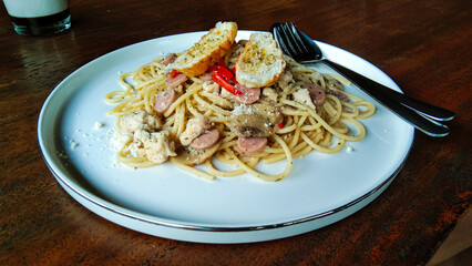 Spaghetti on a white ceramic plate with a wooden table background