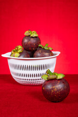 fresh mangostees on a red background at vertical composition