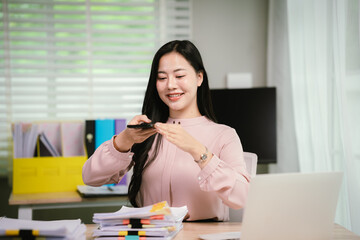 A cheerful businesswoman organizes stacks of documents at her desk, surrounded by charts, folders,...