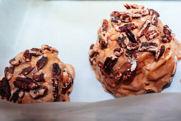 Sweet delicious freshly baked cinnamon buns glazed with caramel cream and nuts on the store counter