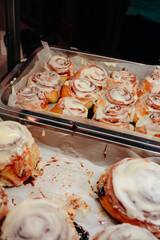 Delicious sweet freshly baked cinnamon buns glazed with butter cream on the store counter