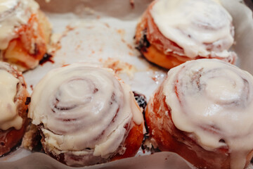 Delicious sweet freshly baked cinnamon buns glazed with butter cream on the store counter