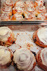 Delicious sweet freshly baked cinnamon buns glazed with butter cream on the store counter