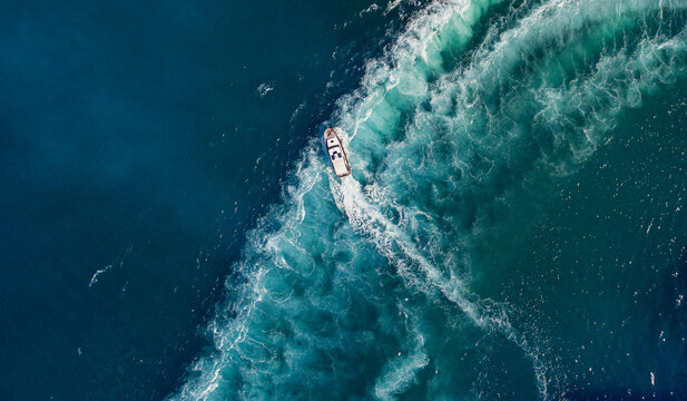 Aerial view of a boat cutting through the deep blue sea, leaving a frothy trail of white and turquoise wake behind, Split, Split-Dalmatia County, Croatia.