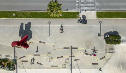 Aerial view of a vibrant promenade with a bold red sculpture contrasting against the pale concrete, dotted with people enjoying the coastal space, Split, Split-Dalmatia County, Croatia.