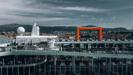 Split, Croatia - 28 April 2024: Aerial view of the cruise ship deck with its stark white structures contrasting against the city's warm terracotta rooftops and distant mountains.