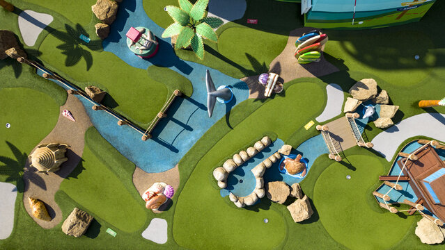 Aerial view of a whimsical miniature golf course, its vibrant green turf dotted with colorful obstacles and winding blue streams, Split, Split-Dalmatia County, Croatia.