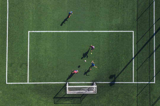 Aerial view of figures playing soccer on a vibrant green field with stark white lines and goalposts, a lively contrast captured from above, Split, Split-Dalmatia County, Croatia.