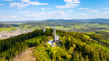An aerial view captures the Svatobor Lookout Tower surrounded by lush forests and rolling hills in...