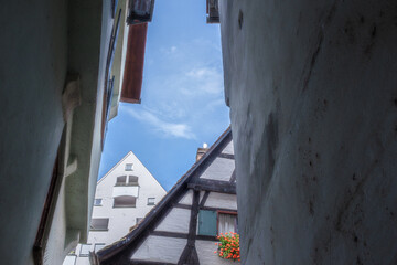 Enge historische Häusergasse mit Durchblick auf Giebelseite schiefes Haus und modernes Gebäude...