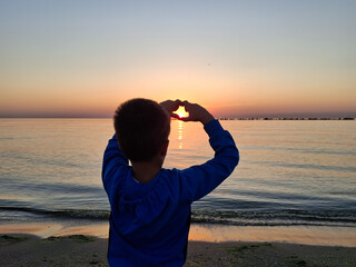 A child and the sun rising over the Black Sea. In Mamaia, Constanta
