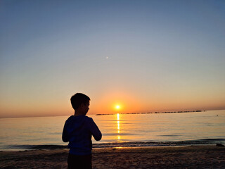 A child and the sun rising over the Black Sea. In Mamaia, Constanta