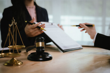 A lawyer consulting with a client in an office, reviewing legal documents and contracts related to...