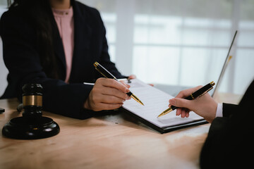 A lawyer consulting with a client in an office, reviewing legal documents and contracts related to...