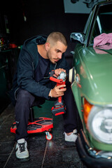 A young man polishing an old-timer car in his garage