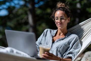A focused woman enjoys working on her laptop while relaxing in a serene outdoor environment, embodying the perfect blend of productivity and leisure in nature.