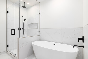 A bathroom with a white standalone soaking tub and wa a walk-in shower with white marble tiles and black faucets.