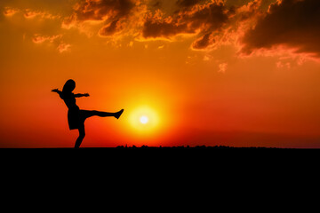 Running Free: Silhouette of a Joyful Woman Jumping at Sunrise in a Summer Sky