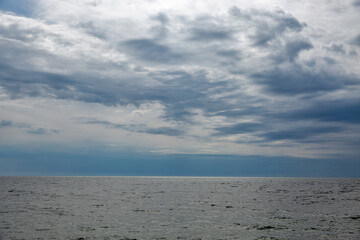 Calm sea horizon under cloudy blue sky