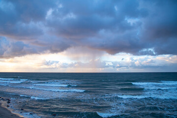Dark sky over the sea. Low clouds over the water in the bay. Background with a tense panorama of nature before a storm at sunset.