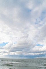 Blue sky with clouds over the sea. Calm landscape on the theme of travel and seaside recreation.