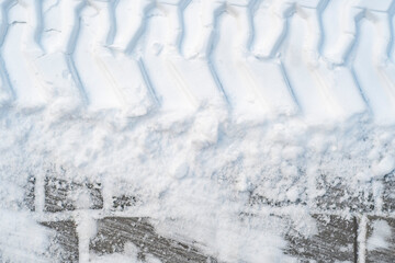 Close-up of tractor tracks on snow-covered cobblestones. Tire tracks on a winter road.