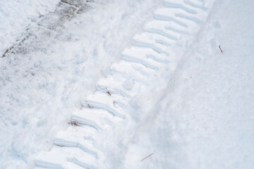 Close-up of tractor tracks on snow-covered cobblestones. Tire tracks on a winter road.
