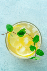 A glass of fresh lemonade, a mocktail with lemon juice, on a blue background, shot from the top with mint