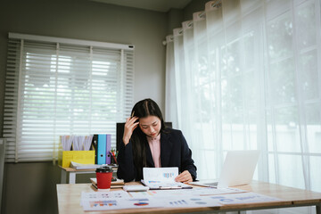 A tired businesswoman sits at her desk, visibly stressed and overworked, struggling with burnout,...