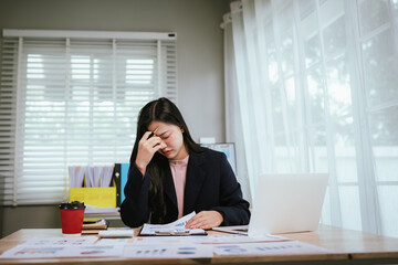 A tired businesswoman sits at her desk, visibly stressed and overworked, struggling with burnout,...