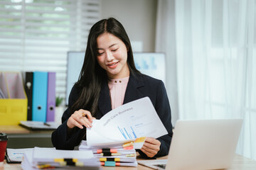 A professional woman sits at a bright, modern office desk, smiling while efficiently sorting...