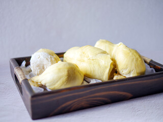 A yellow durian that has been peeled off to reveal the tasty yellow flesh of the durian. Durian fruit on wooden basket